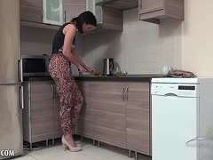 Dunkelhaarige Hausfrau masturbiert in der Küche mit Utensilien
